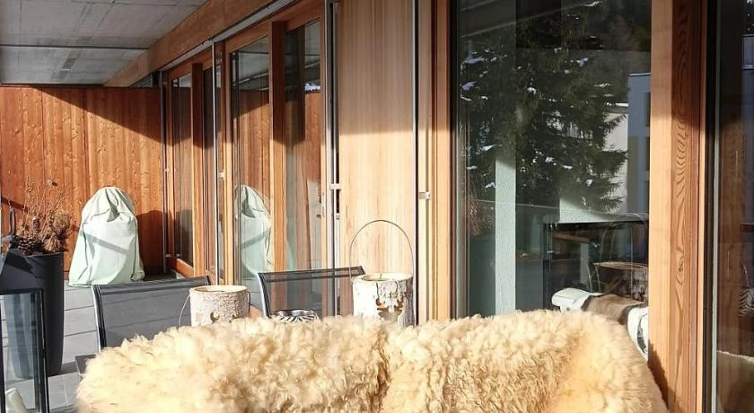 A wood-clad Davos balcony with a sheepskin throw and mountain view