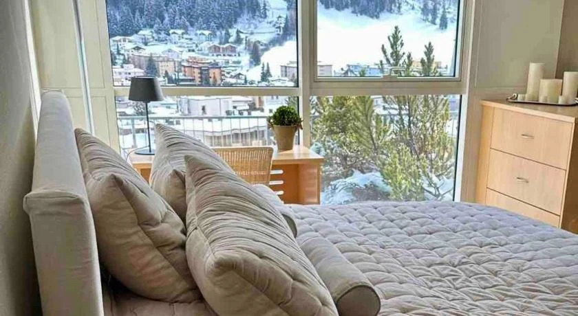 A Davos apartment bedroom with a floor-to-ceiling window over the snowy valley