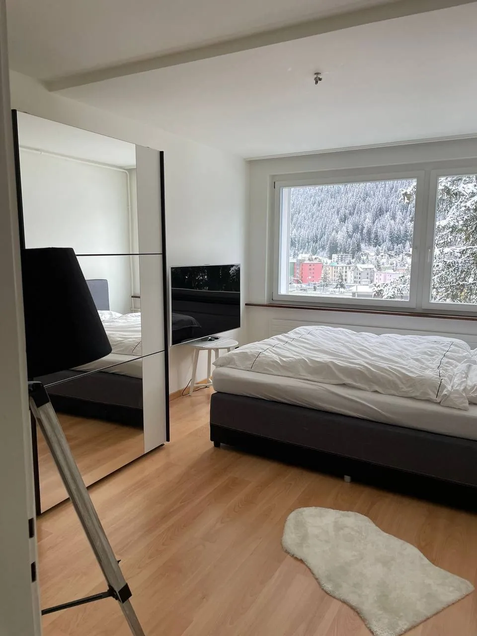 Double bedroom with a mirrored wardrobe and a window looking over Davos and snowy forest