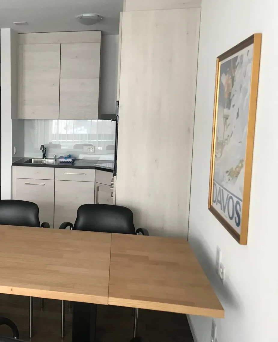 The same meeting table seen from the other side, with a fitted kitchenette behind it