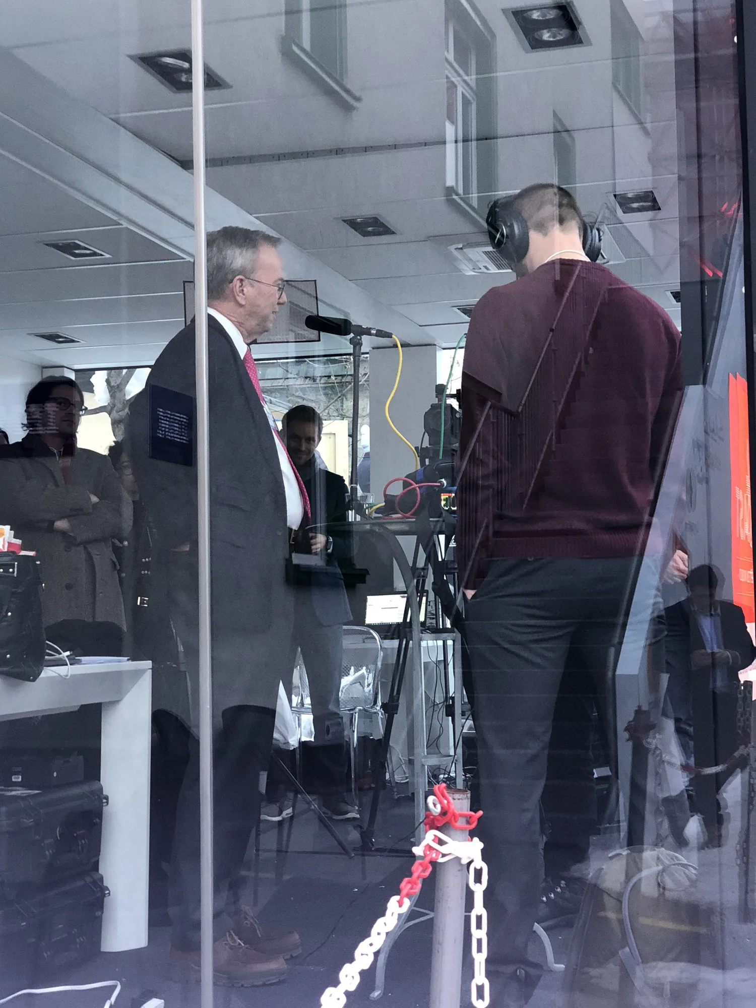 A broadcast interview filming from a glass-walled Promenade pavilion
