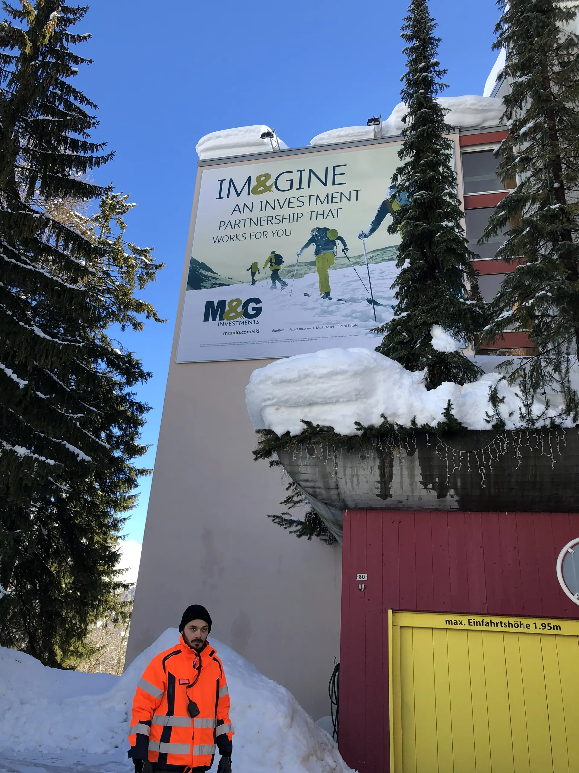 A corporate sponsor's signage on a Davos building, security staff on the pavement below