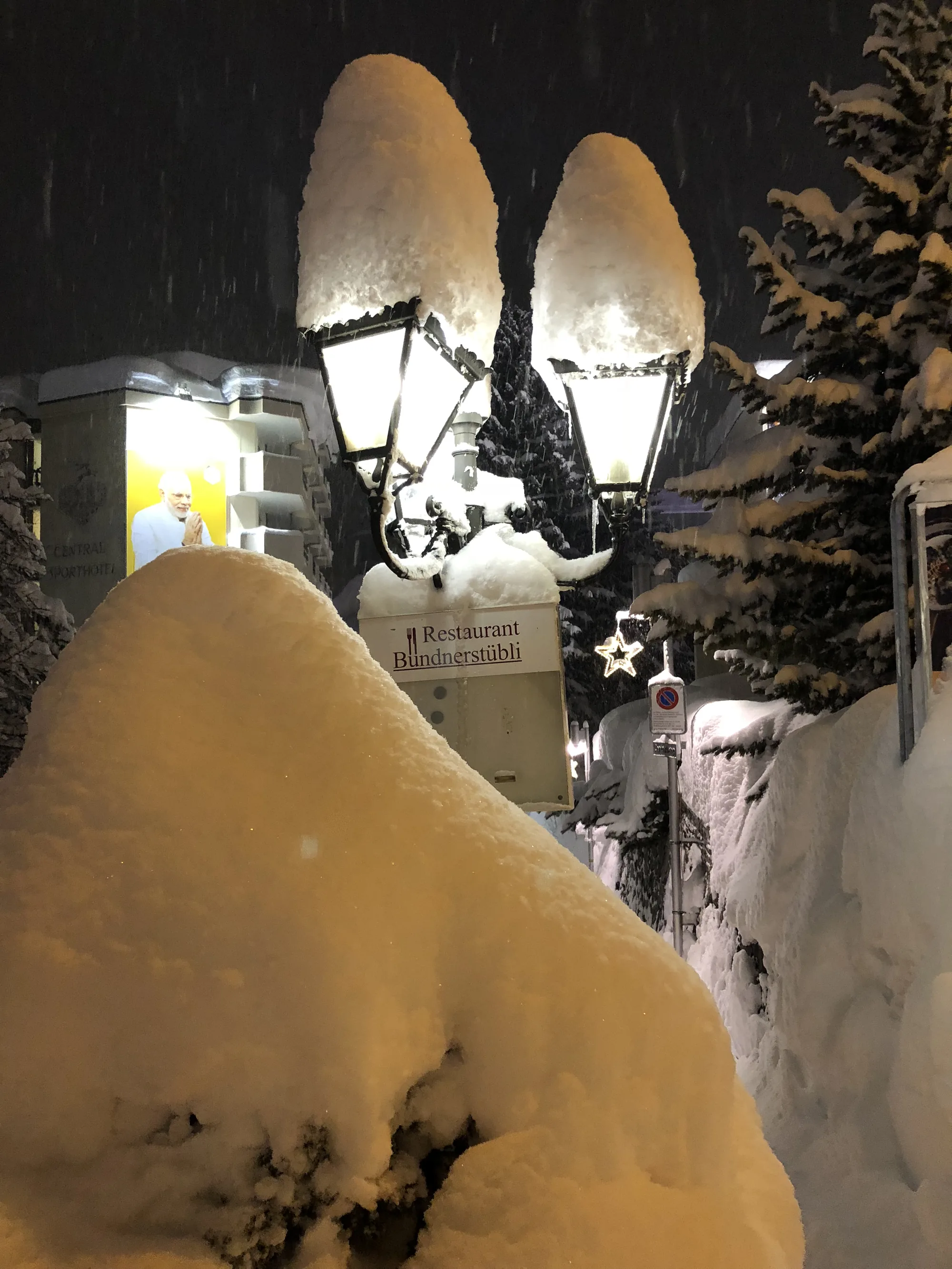 Restaurant lanterns lit along a snowy Davos street at night