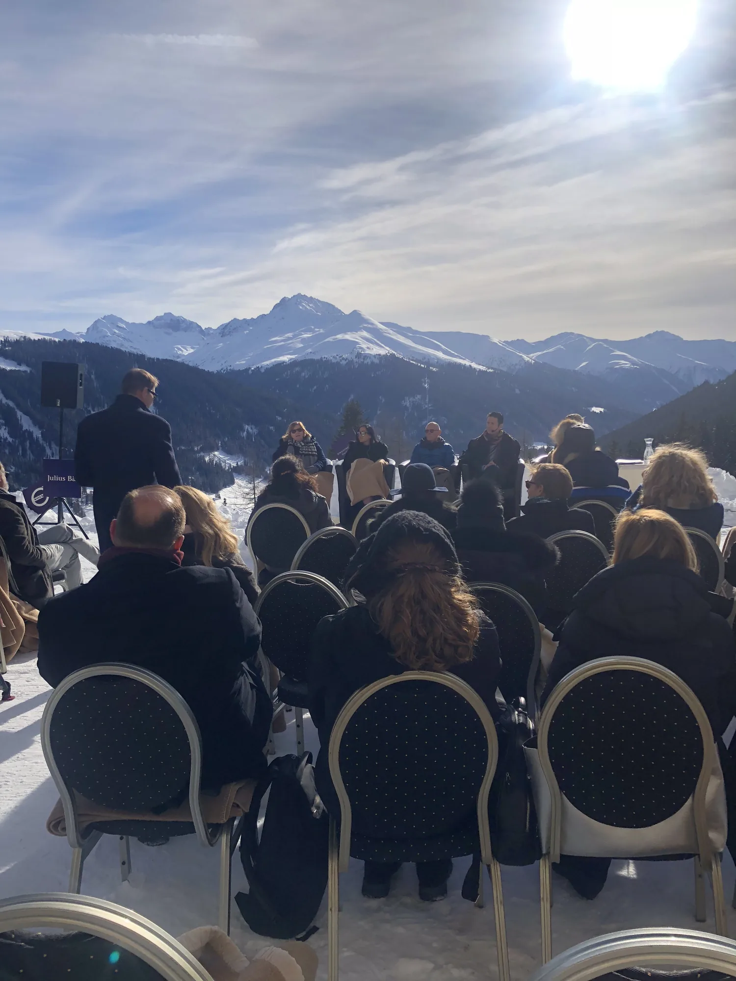 Guests seated outdoors in the sun at a past Swedish Lunch, mountains behind